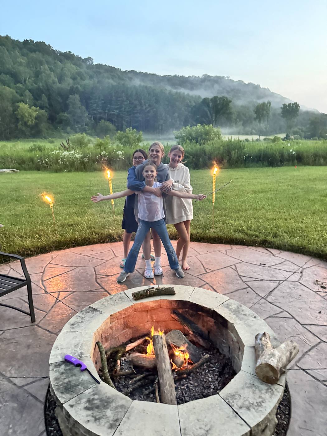 Children with sparklers around a fire pit at dusk